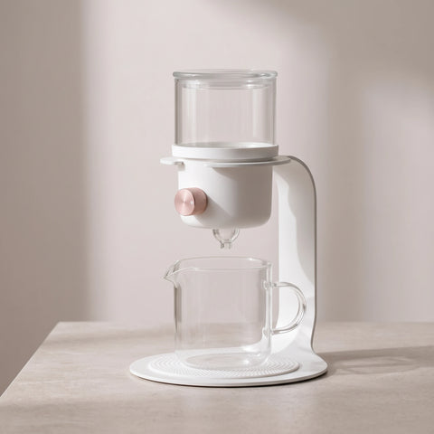 White glass tea and coffee brewer on a stone side table