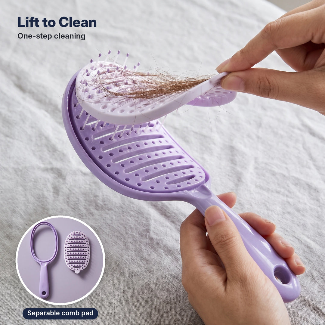 Hands lifting the removable comb pad with hair out of a purple self-cleaning hair brush